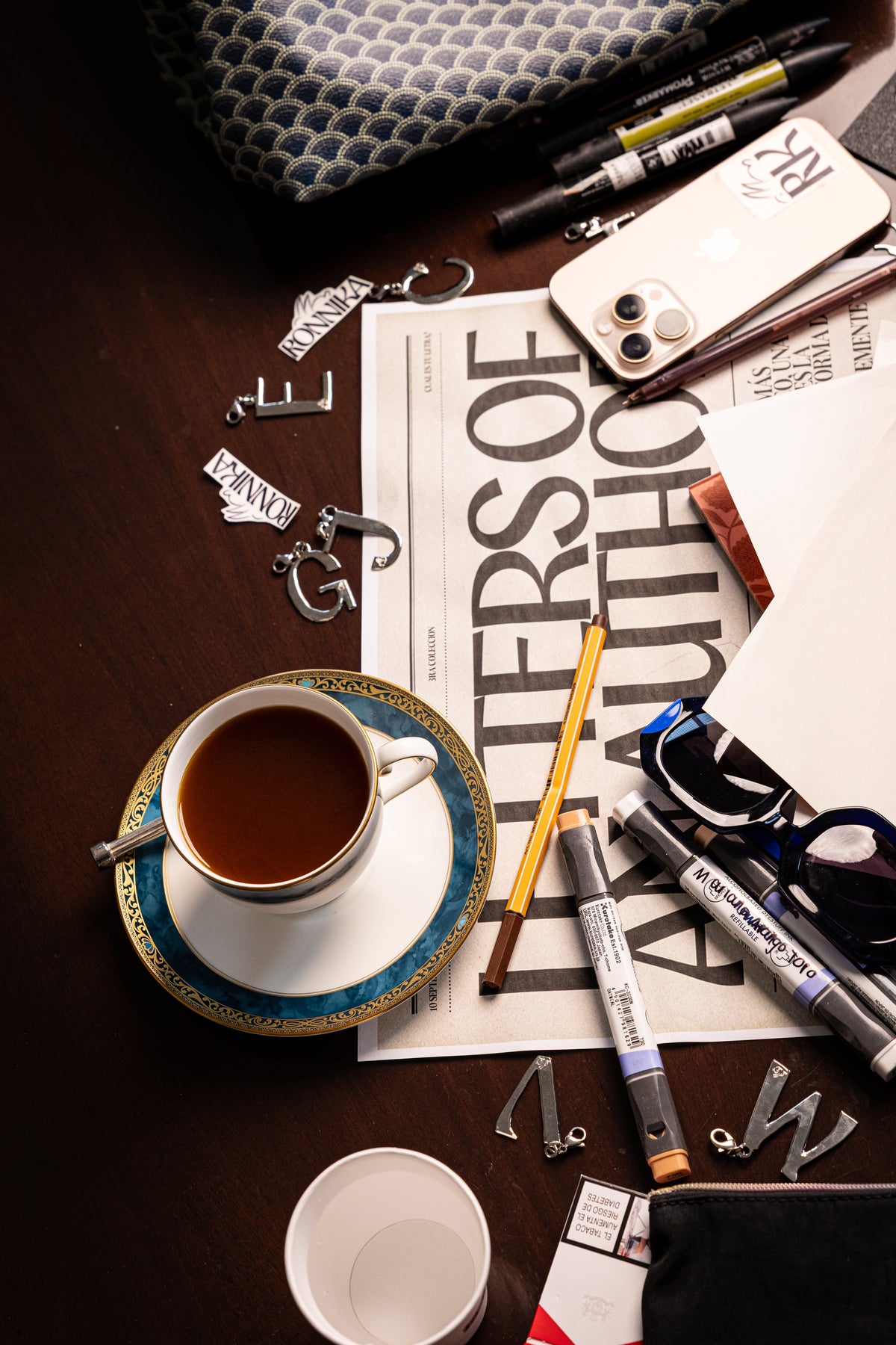 Charms de letras RONNIKA junto a una taza de café y la revista Letters of an Author